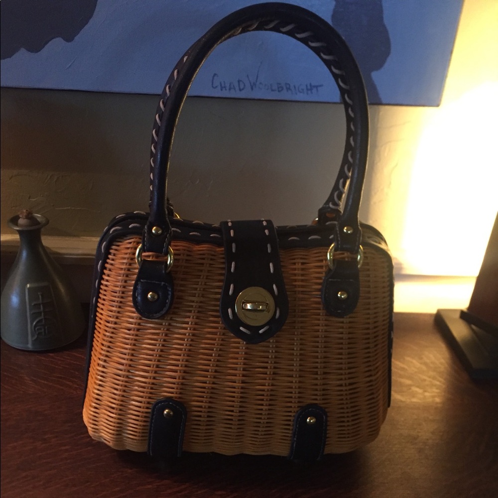 Straw bag with black trim and white stitching.